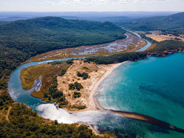 A stunning aerial view of a scenic sandy beach, lagoon, and surrounding lush hills in Primorsko, Bulgaria.