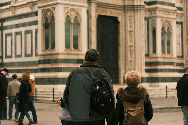 People walking past a large ornate building.