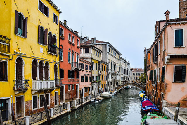 Vibrant buildings line a tranquil canal in Venice, showcasing classic architecture and picturesque gondolas.