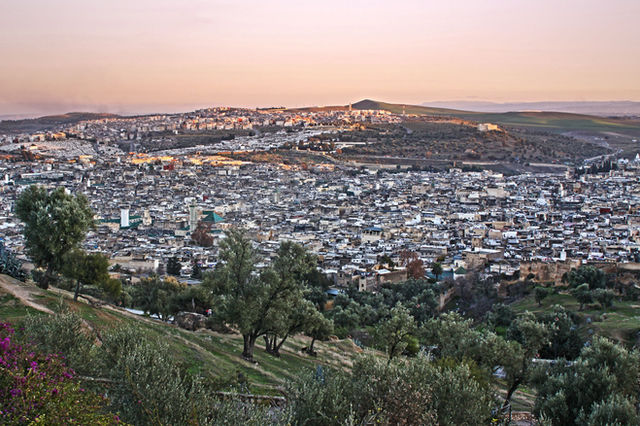 Beautiful sunset view over Fes, Morocco with a sprawling cityscape and hills in the background.