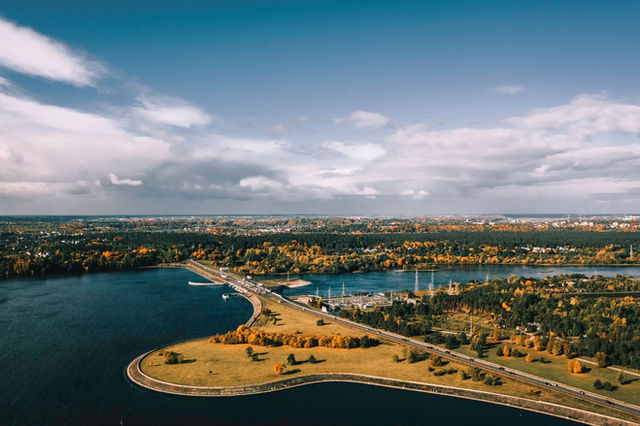 Stunning aerial view of Kaunas, Lithuania, showcasing autumn colors, rivers, and cityscape under a blue sky.