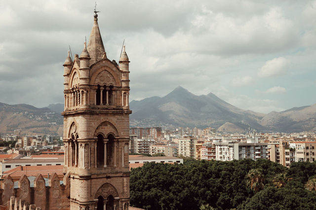 Explore the cityscape of Palermo, Sicily with a focus on its historic architecture and scenic backdrop.