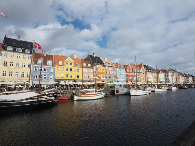 Colorful buildings line a canal with boats in copenhagen.