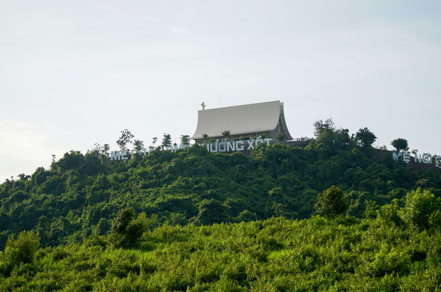 Building on a lush green hilltop with white lettering.