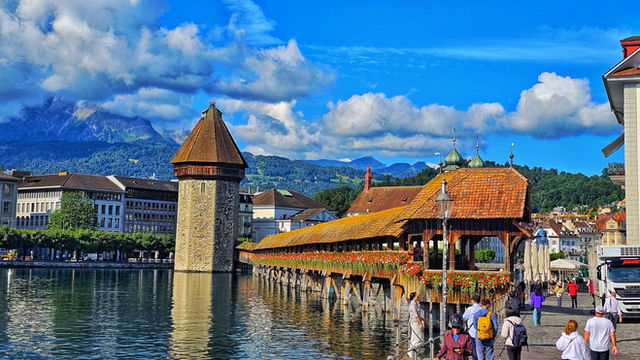 Covered wooden bridge over a river with mountains.