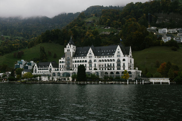Grand white building on a lake with hills.
