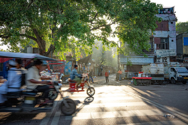 Vibrant morning hustle on Delhi streets capturing e-rickshaws and pedestrians in motion.