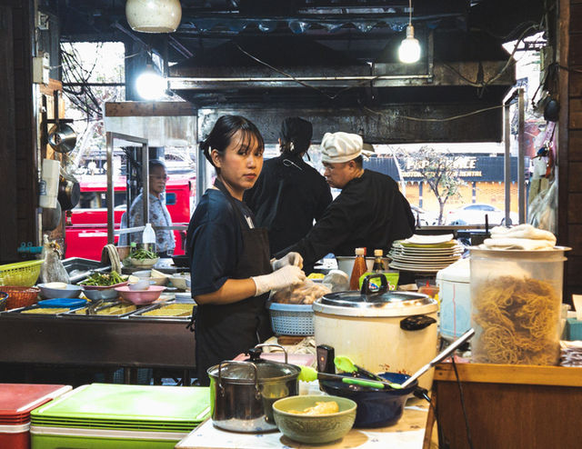 Street food vendor preparing traditional Thai dishes at a bustling market in Chiang Mai, Thailand.