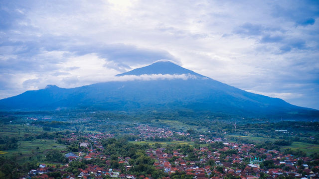 Stunning aerial view of Mount Salak with a village nestled below, captured in West Java, Indonesia.