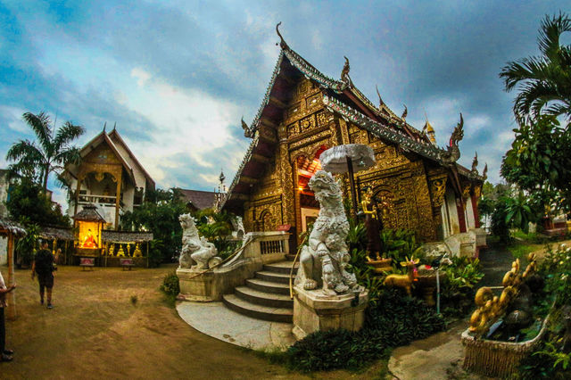 A beautifully detailed Thai temple at dusk, showcasing traditional architecture and sculptures in Chiang Mai.