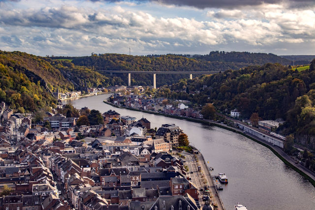 Explore the picturesque town of Dinant, Belgium with its scenic river and surrounding landscape captured from above.