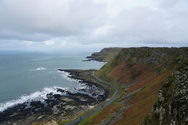 Coastal road winds along rugged cliffs by the sea