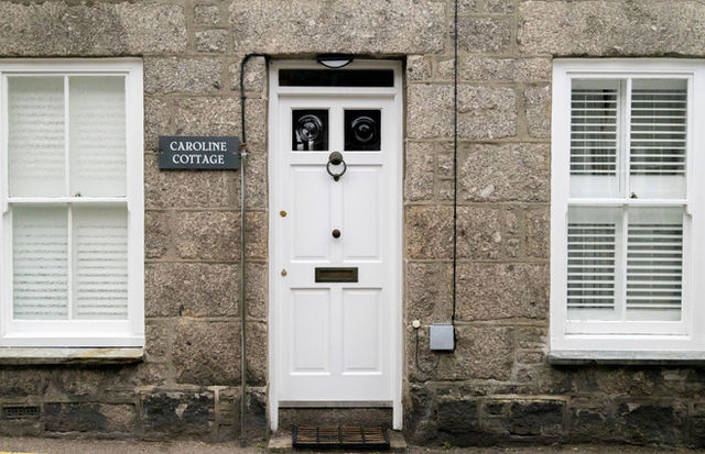 Elegant traditional entrance of Caroline Cottage in Penzance, Cornwall, featuring a symmetrical white door and stone facade.