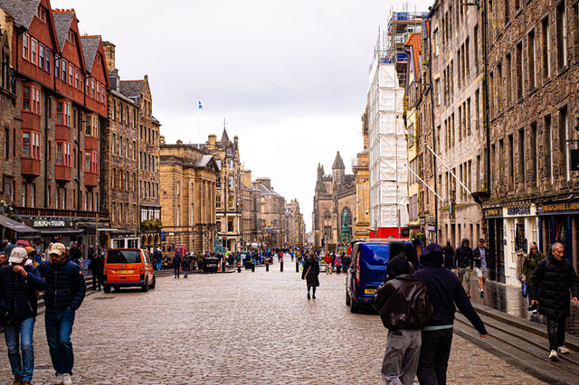 Cobblestone street in Edinburgh bustling with people and surrounded by historic architecture.