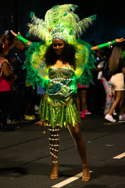 A dancer lit from within, green sequins against a night street