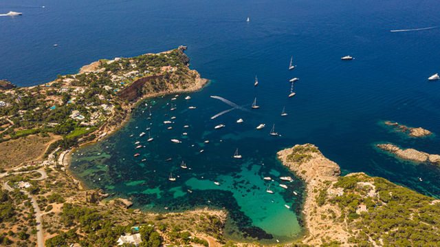Stunning aerial view of Ibiza's coastline with turquoise waters and yachts.