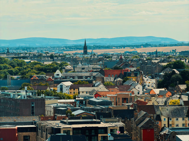 A scenic aerial view of Edinburgh, Scotland's charming rooftops and distant hills.