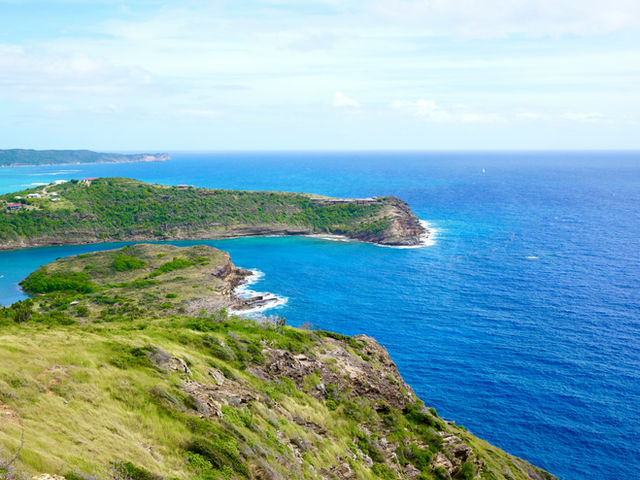 green grass field near blue sea under blue sky during daytime