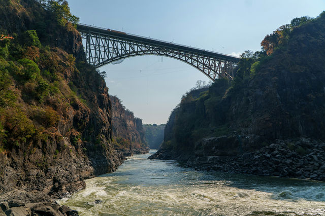 Arch bridge spans a rocky gorge above a river