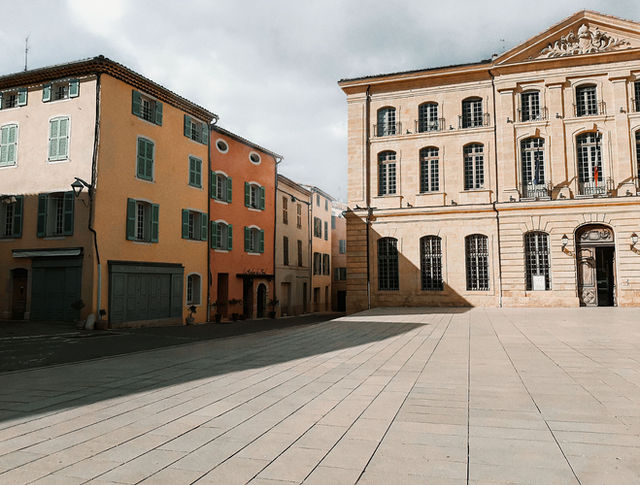 Charming European architecture in a sunlit square, showcasing colorful Provence style buildings.