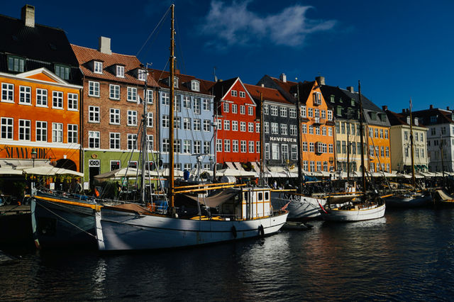 Colorful buildings line canal with boats in copenhagen.