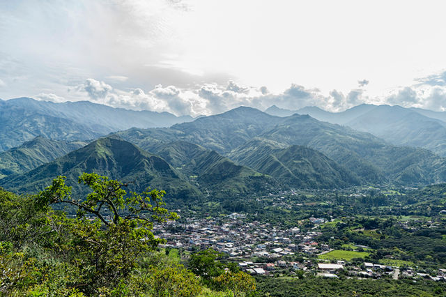 houses on green grass field near mountains under white clouds during daytime