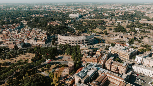 An expansive aerial view of Rome highlighting the iconic Colosseum amidst the historic cityscape.