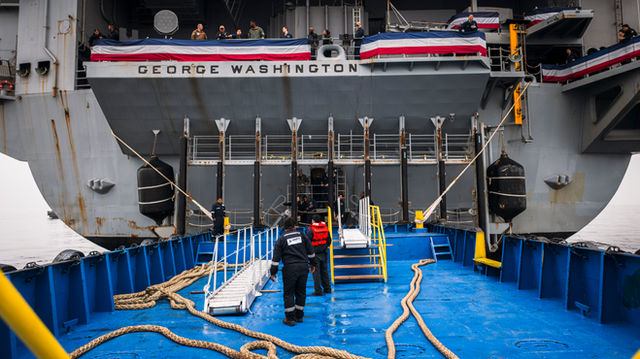 A barge connects to the stern dock of Nimitz-class aircraft carrier USS George Washington (CVN 73) while anchored off the coast of Lima, Peru, June 20, 2024. George Washington is d