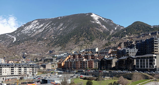 Snow-capped mountain overlooks a town with modern buildings.