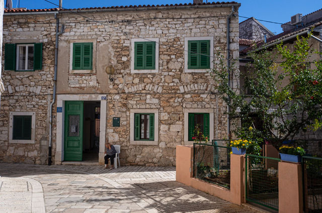 Stone house with green shutters in a picturesque street in Poreč, Croatia.