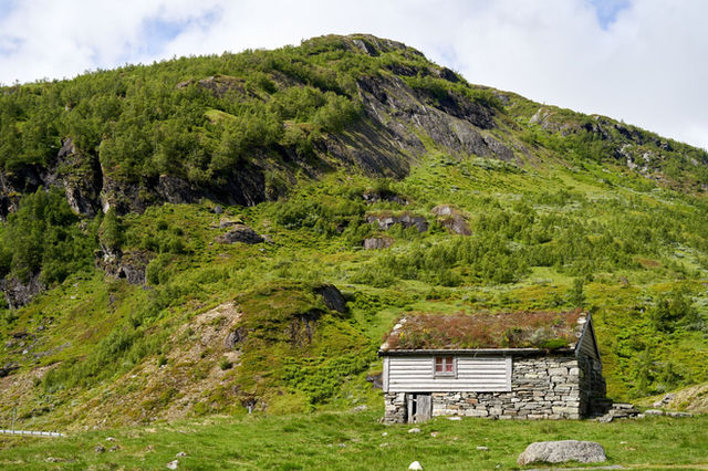 Idyllic stone cottage amidst green hills in Vestfold og Telemark, Norway, exuding tranquility and rustic charm.