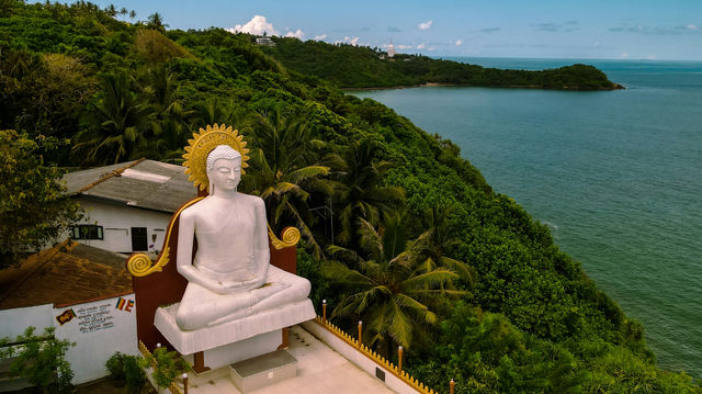a statue of a person sitting on a bench by a body of water