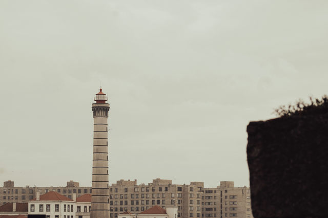 Tall lighthouse stands against a cloudy sky.
