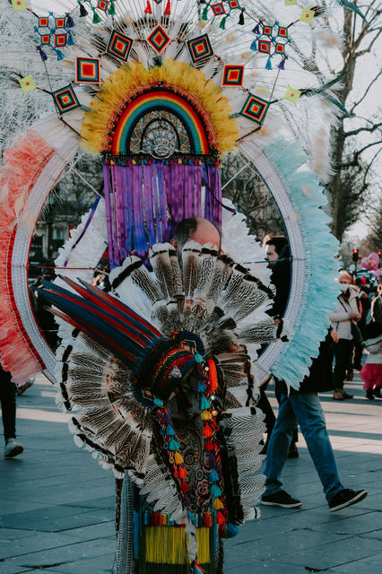 A mirrored rainbow arc and white plumes, carried through a winter street