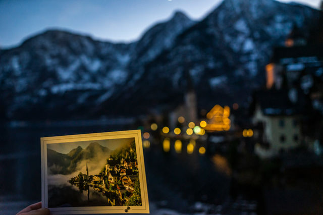 A postcard of a village with mountains in the background.