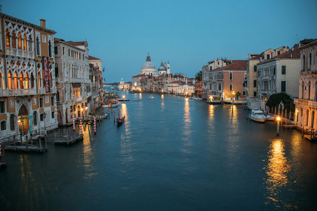 Venice grand canal at dusk with illuminated buildings and boats.