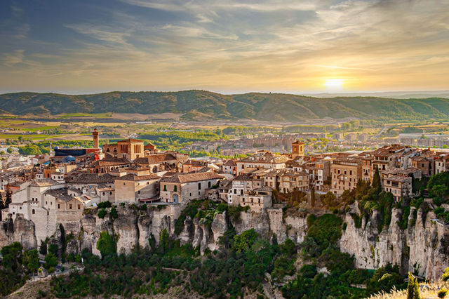 Stunning view of Cuenca, Spain with dramatic cliffs and historic buildings at sunset.