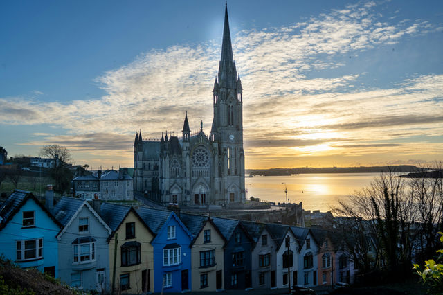 Discover the charm of Cork, Ireland, where pastel townhouses line up beneath the majestic Gothic spire of St. Colman’s Cathedral. A golden sunrise over the harbor completes this postcard-perfect Irish