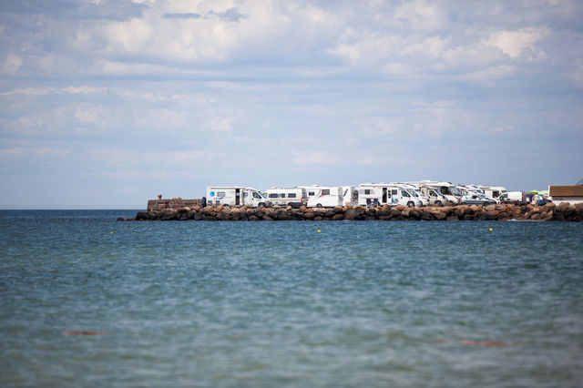 Mobile homes parked closely together on a pier illustrating the paradox that the more people get out to enjoy the open environment with these huge vehicles the less open space there is left to enjoy.