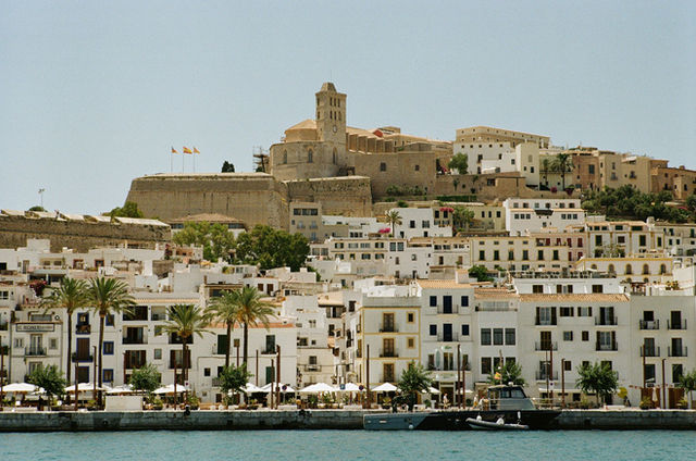 View of historic Dalt Vila in Ibiza Town, Spain, with whitewashed buildings and clear blue sky.