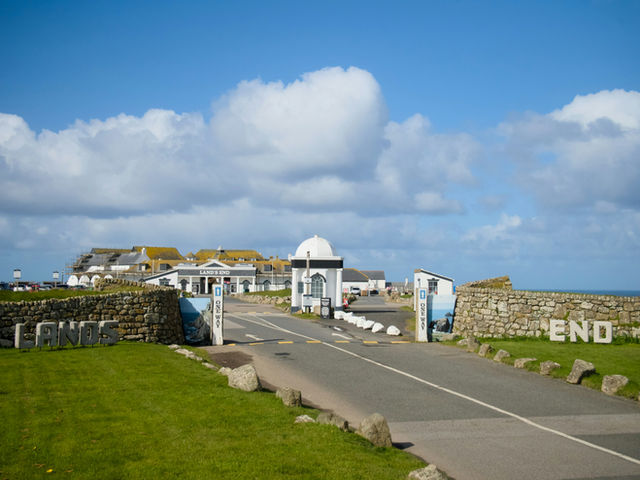 Road leading to buildings with stone walls under sky