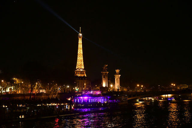 Eiffel tower illuminated at night with a beam of light
