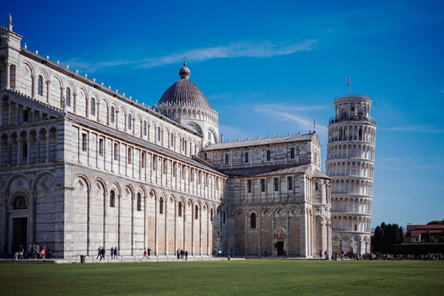 Iconic view of the Leaning Tower and Pisa Cathedral in Tuscany, Italy, on a clear sunny day.