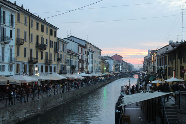 Scenic evening view of Naviglio Grande canal in Milan with vibrant street life.