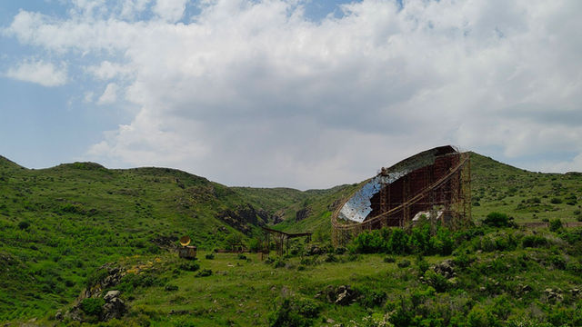 Explore the scenic greenery and abandoned satellite dish in Orgov, Armenia's rolling hills.