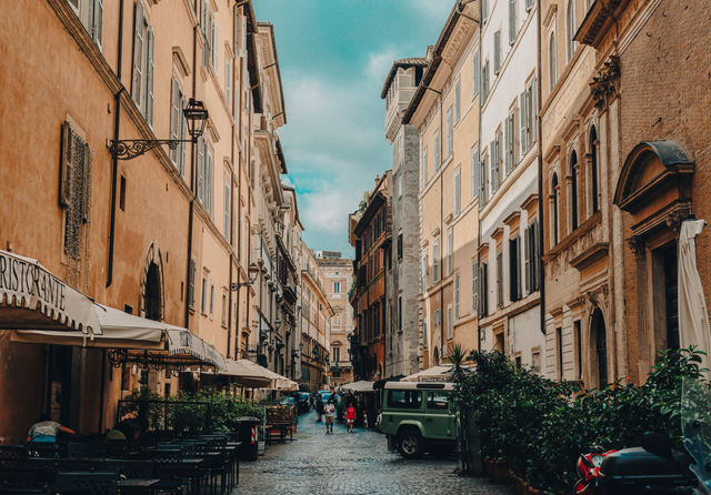 A picturesque cobblestone street in Rome with outdoor cafes and historic architecture.