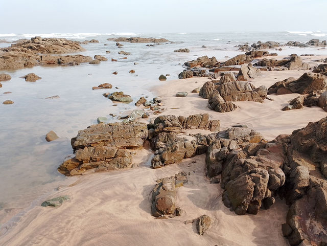 Rock formations and sandy shores at low tide in Casablanca, Morocco, showcasing natural beauty.