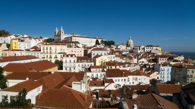 Hilly cityscape with tiled roofs under blue sky