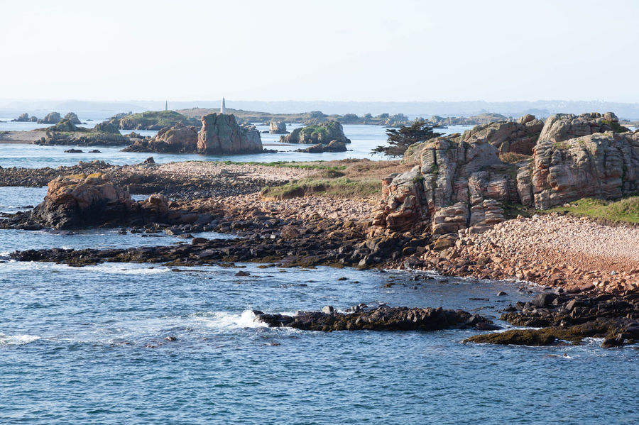 Aerial view of rocky coastline on Île-de-Bréhat in Brittany, France with lush landscape and clear waters.