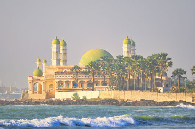 Mosque on an island with palm trees and ocean waves